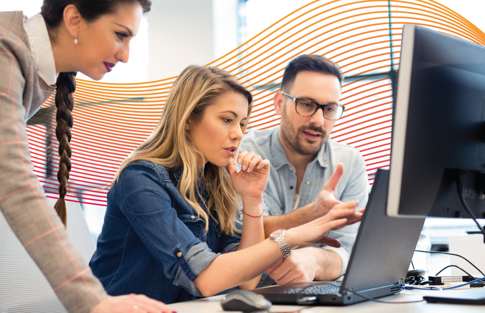 People collaborating around a laptop and computer